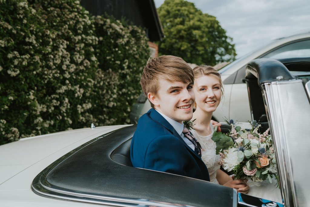 Bride and groom in a Triumph classic wedding car