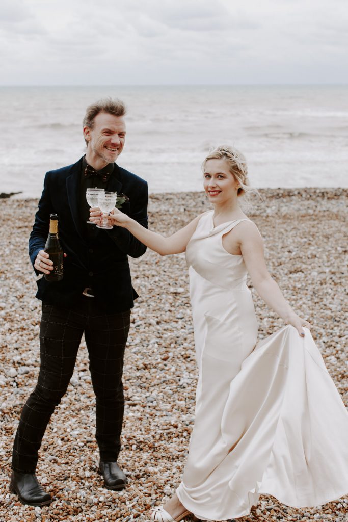 Bride and groom having a glass of wile on a beach in Hastings