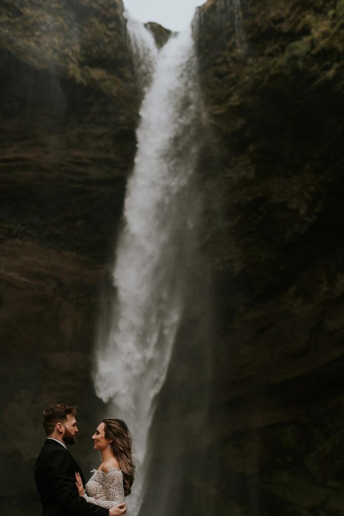 Young married couple having wedding photos taken at Gljufrabui waterfall in Iceland