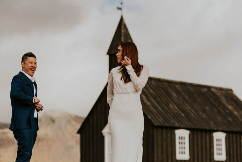 Married couple having their photo taken outside a black church in Budir in Iceland