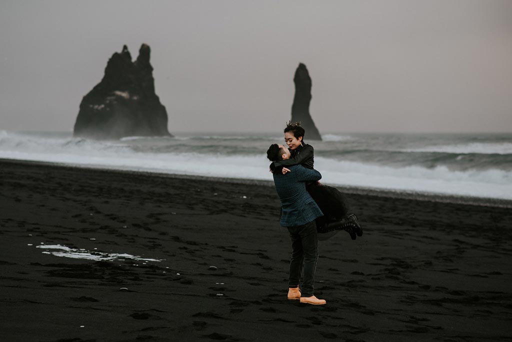 Young couple hugging at Reynisfjara black sand beach in Iceland