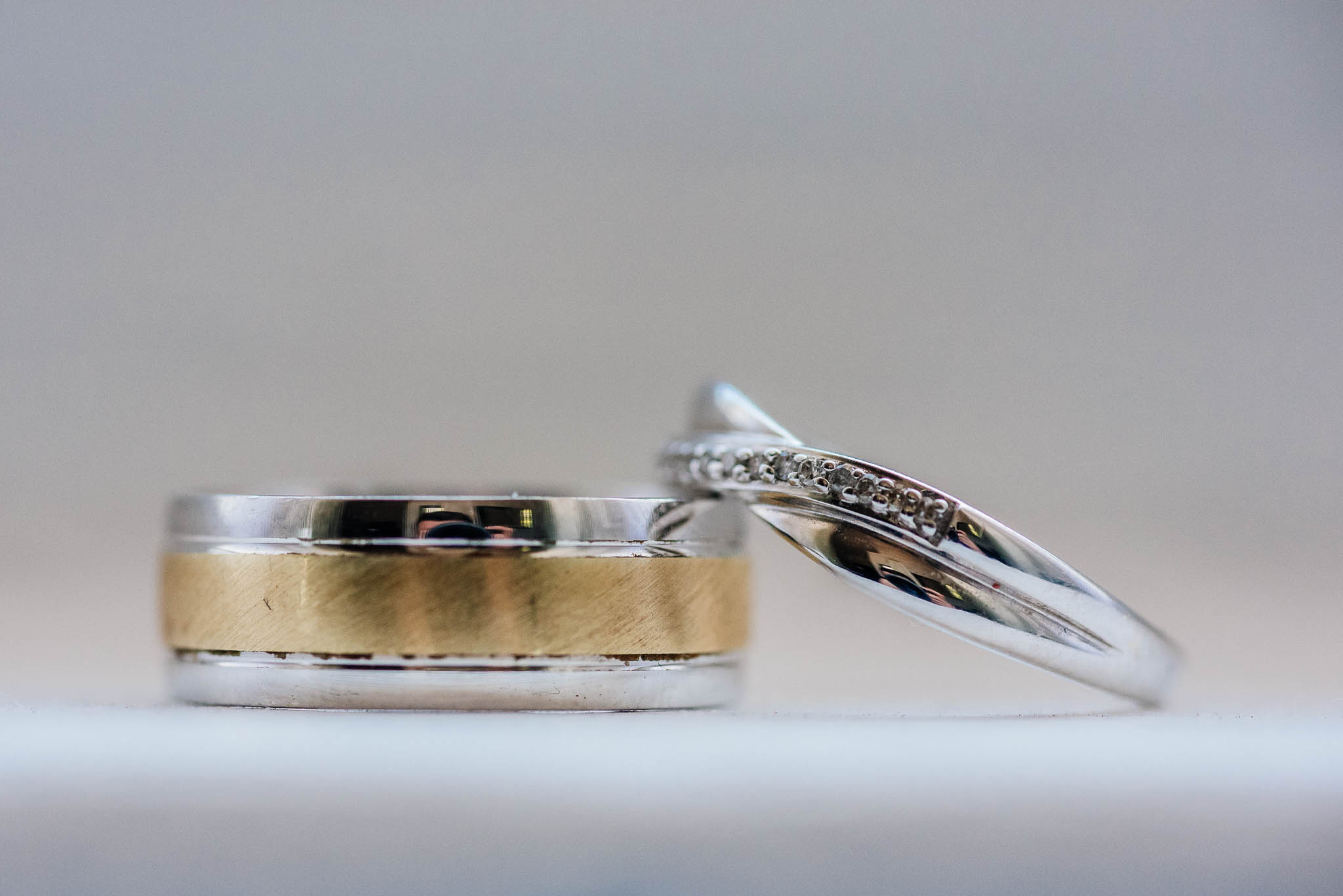 A beautifully captured close-up image of two wedding rings, showcasing the intricate details and textures of the rings. The rings are resting on a neutral, blurred background that highlights their beauty and symbolizes the unity and everlasting love they represent.